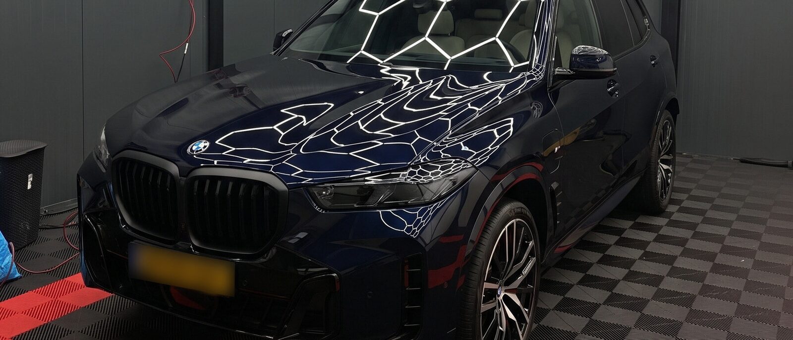 Donkerblauwe BMW X5 van voren op de opstelplaats, met het ledraster in de motorkap